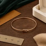 Bracelet rose or 18 carats, jonc minimaliste, sur table en bois